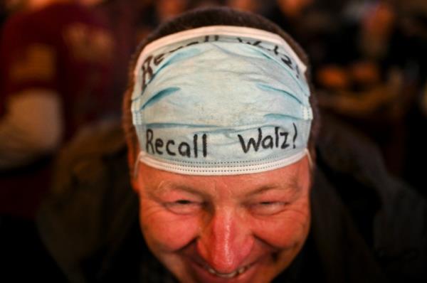 A man with a covid mask with "Recall Walz!" written on it in marker.