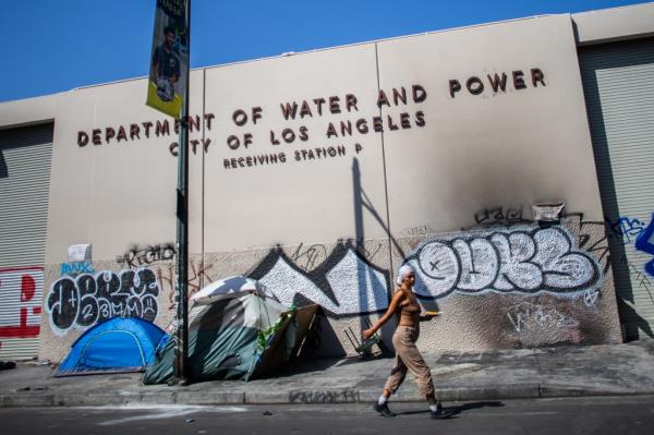 A homeless person walks past an encampment in Skid Row, downtown Los Angeles, California, on July 26, 2024.