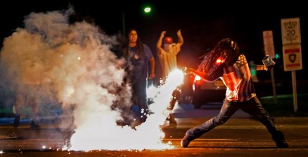 A tear gas canister is thrown back at police during a protest following the fatal shooting of Brown on Aug. 13, 2014.