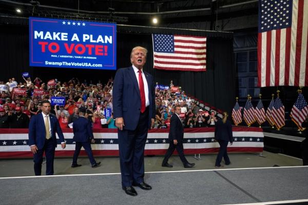 Former President Do<em></em>nald Trump speaking at a campaign rally in Bozeman, Montana, with a crowd on bleachers behind him and American flags hung from the ceiling, during his 2024 presidential run