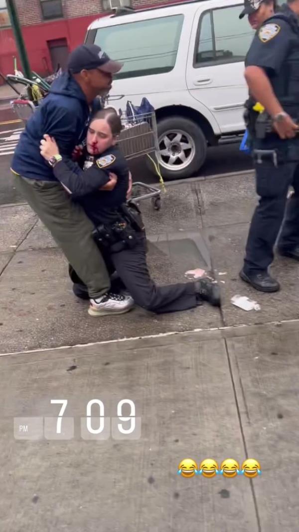 The female police officers leans on a bystander at the scene after she's punched.