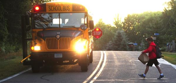 A boy crossing the street as a school bus idles near Brainerd, Minn.